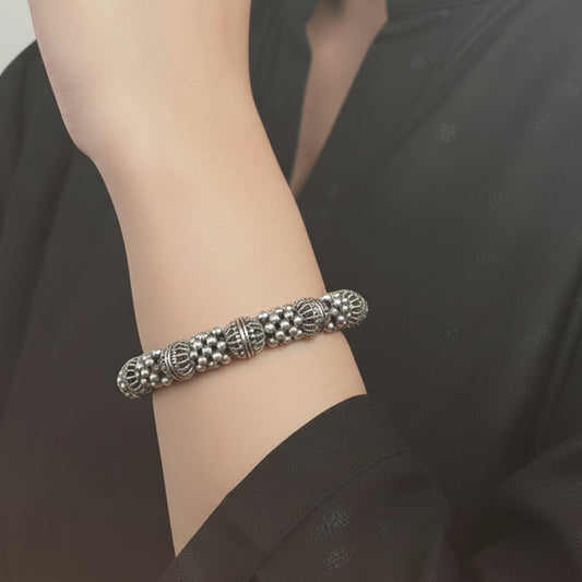 Silver bangles with jhumkas on a black background, featuring the brand 'Saheli'.
