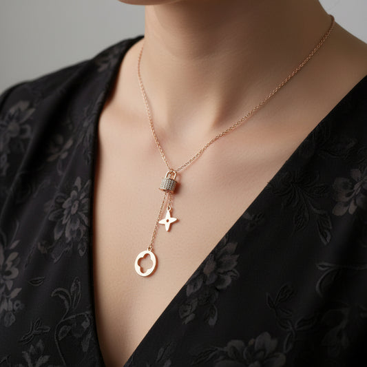 Gold necklace with star and circular pendant on a branded card against a dark background