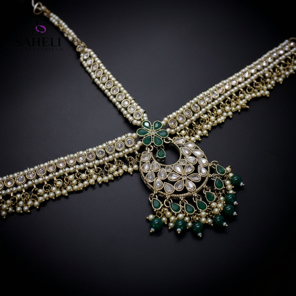 Ornate necklace with green gemstones on a dark background, featuring the brand 'Saheli'.