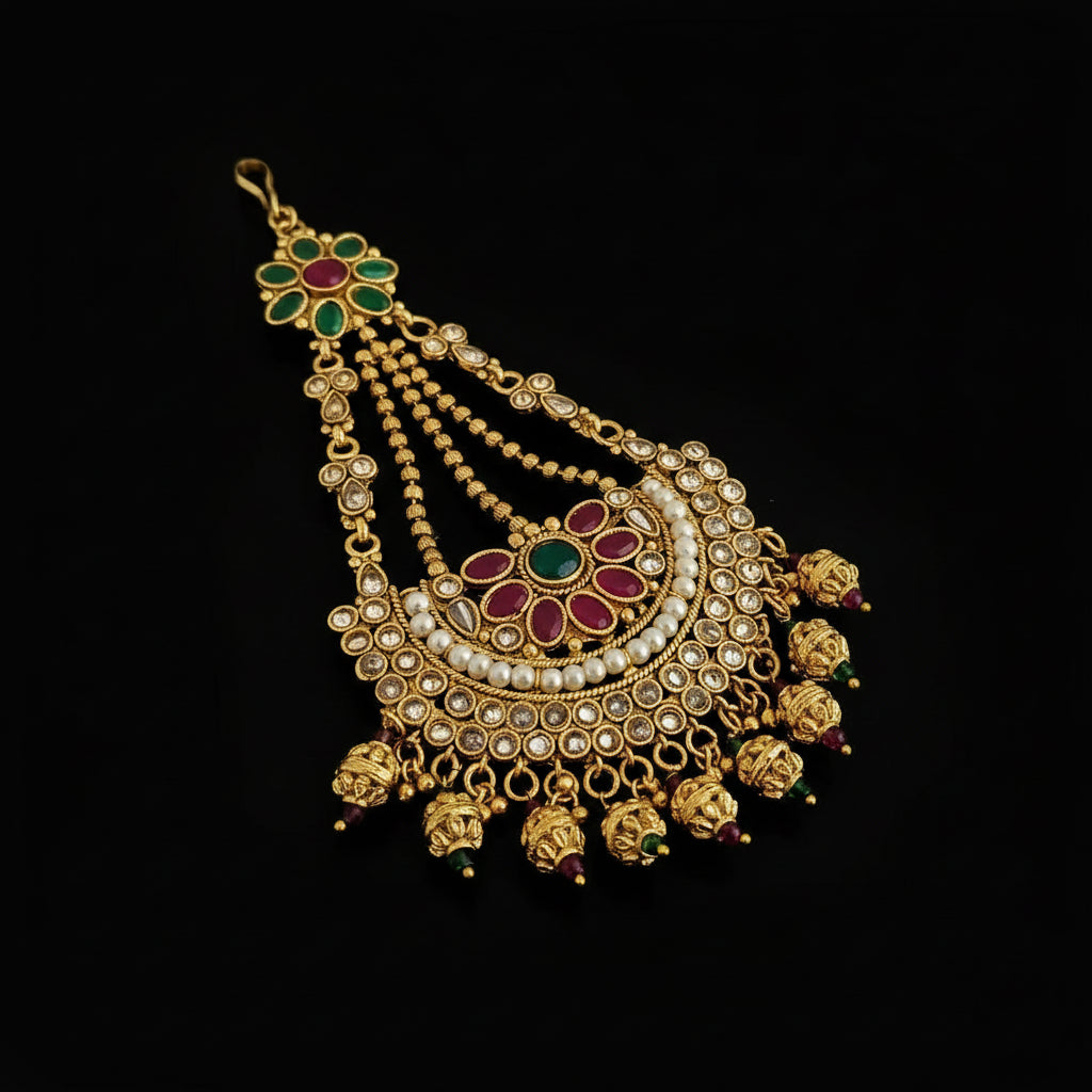 Ornate gold necklace with red and green gemstones on a black background