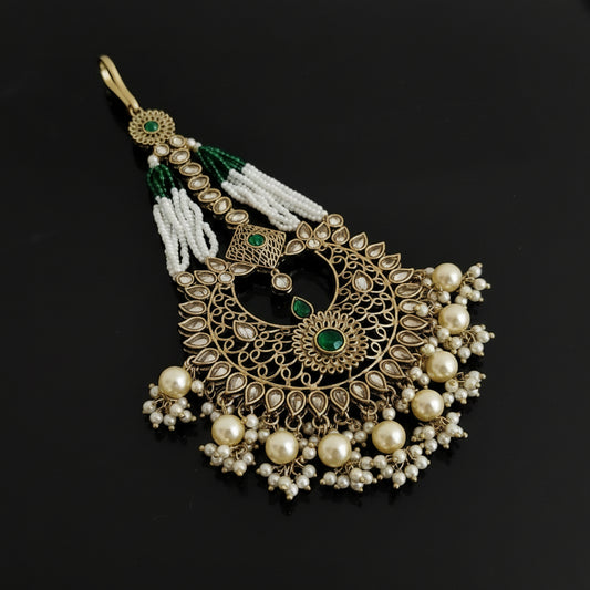 Decorative pendant with pearls and green stones on a black background