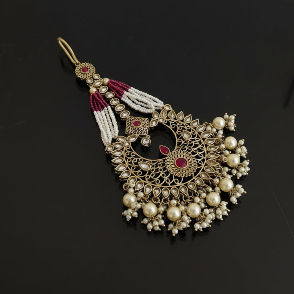 Decorative gold earring with pearls and red stones on a black background