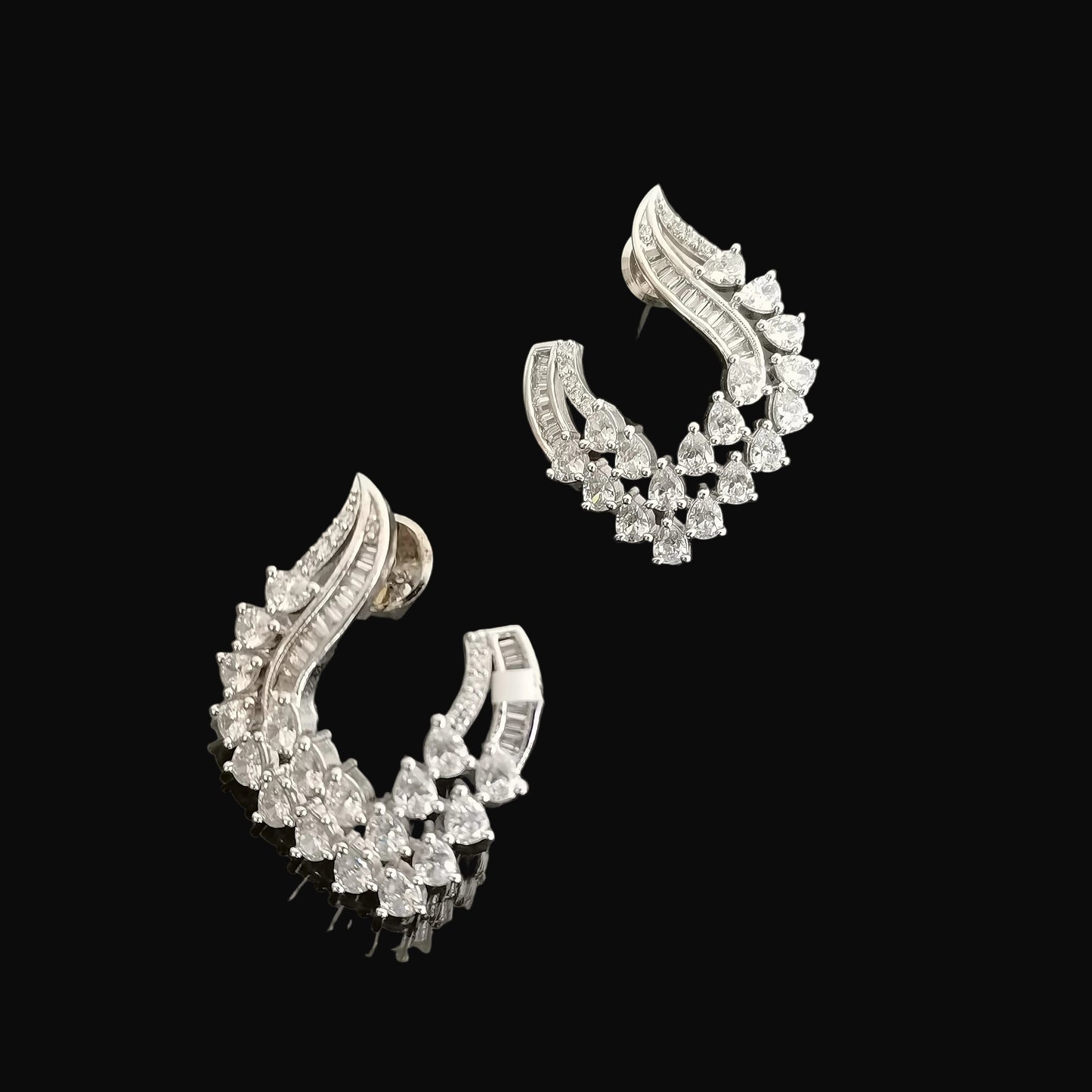 Pair of silver earrings with gemstones on a gray background, featuring the brand 'Saheli'.