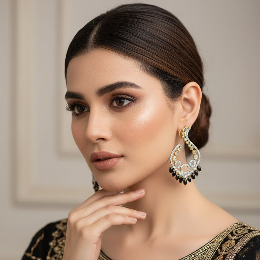 Decorative earrings with gold and silver details on a gray background, featuring the brand 'Saheli'.