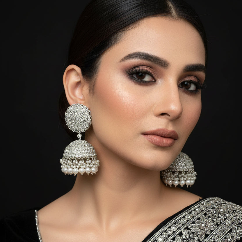 Pair of silver and pearl earrings on a black stand