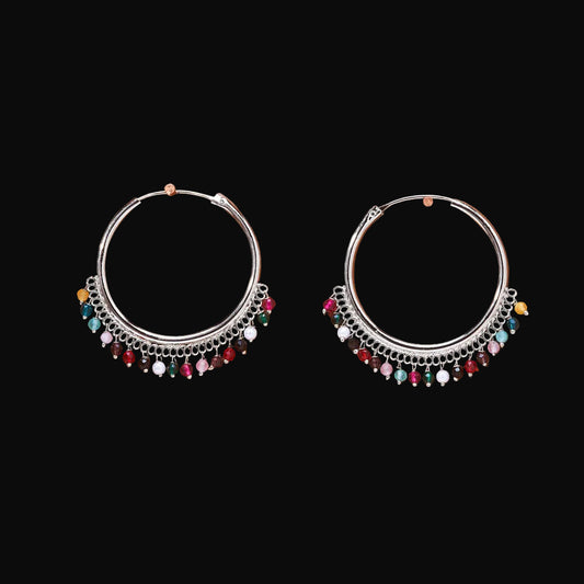 Pair of silver hoop earrings with colorful beads on a brown background