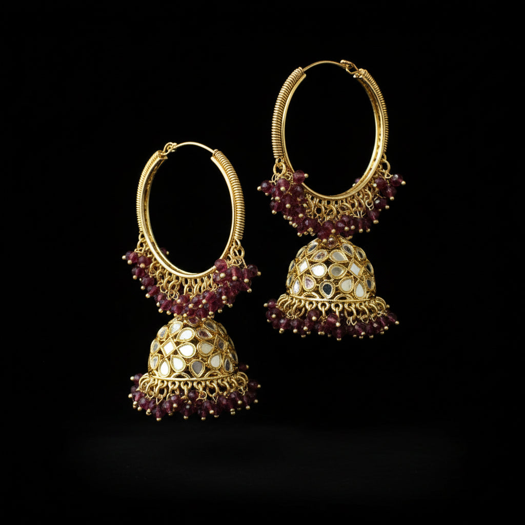 Gold hoop earrings with red gemstones on a black background