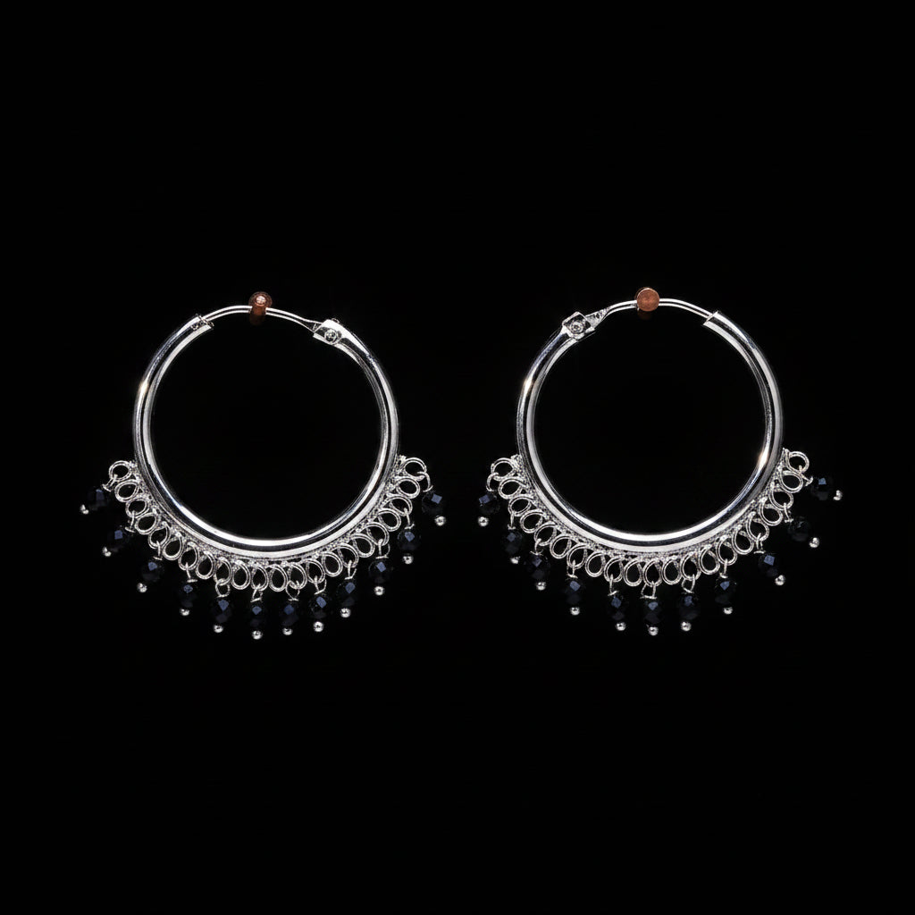 Pair of silver hoop earrings with black beads on a brown textured background