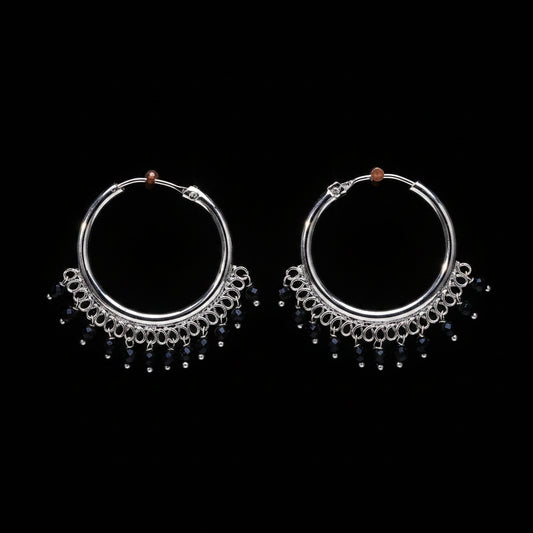 Pair of silver hoop earrings with black beads on a brown textured background