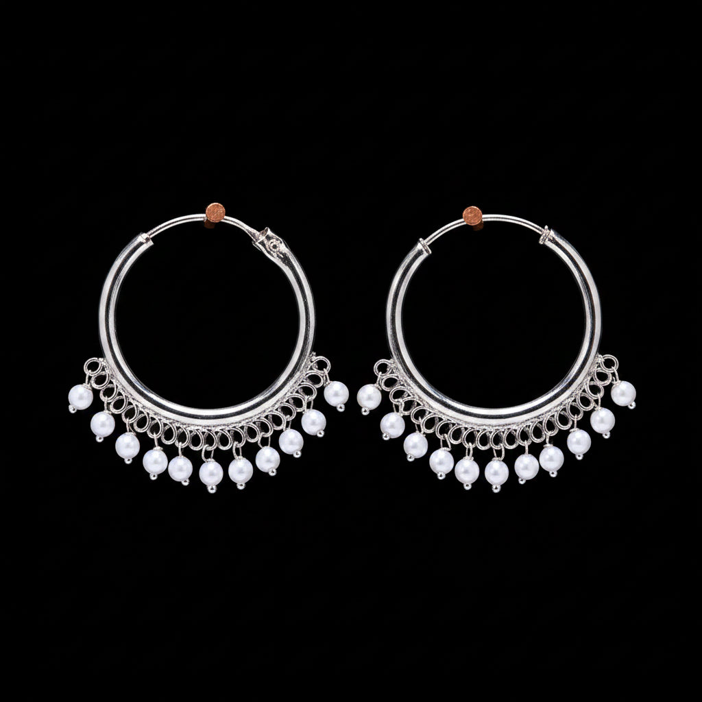 Pair of silver hoop earrings with pearl-like beads on a brown background