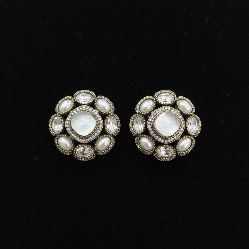 Decorative earrings in a clear plastic package held by a hand on a white surface.