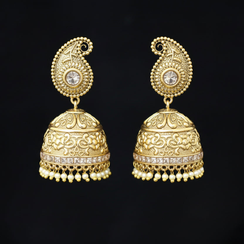 Gold jhumka earrings on a gray stand with 'SAHELI' branding.