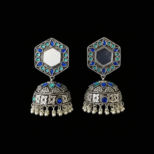 Ornate silver earrings with blue and green gemstones on a black background