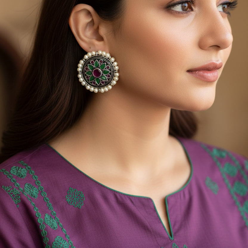 Pair of earrings with floral design and pearl accents on a gray background