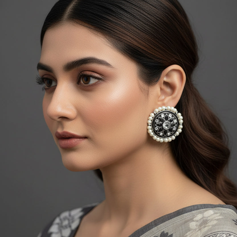 Pair of earrings with black and silver circular design on a dark background