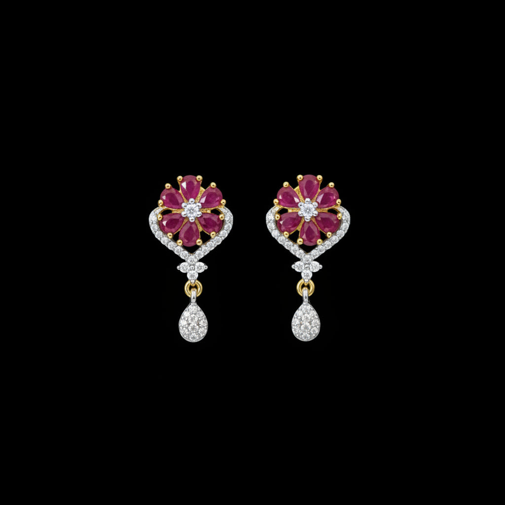 A pair of gold and white stone drop earrings with pink flower-shaped tops, displayed on a dark gray velvet jewelry stand against a dark gray background.