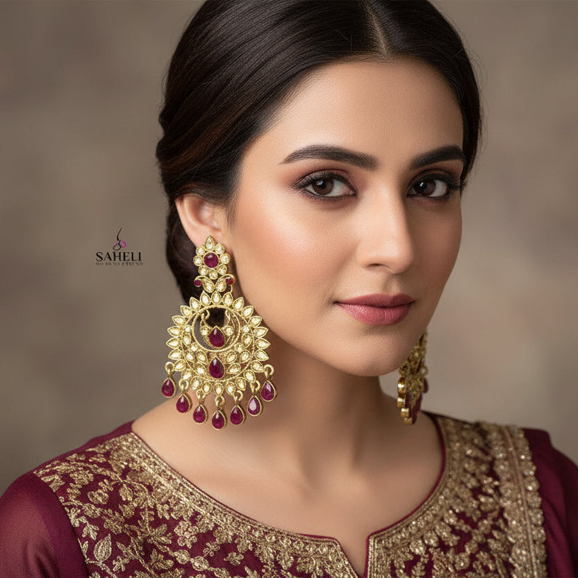 Ornate gold earrings with red stones on a dark background, featuring the brand 'SAHELL'.