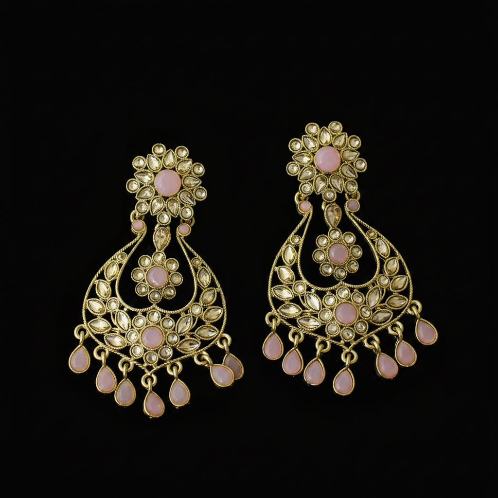 A pair of gold-toned traditional Indian chandbali earrings embellished with pink stones, displayed on a dark reflective surface. The brand logo 'SAHELI MY BEST FRIEND' is visible in the top left corner.