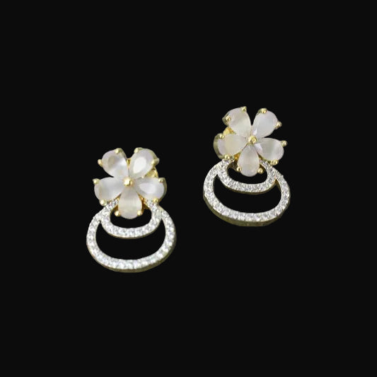 Floral earrings with gemstones on a gray textured surface