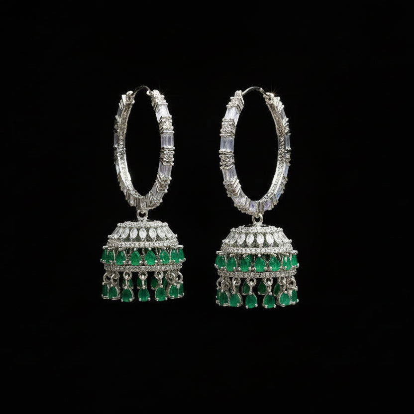 Pair of silver and green earrings on a gray stand with 'Saheli' branding.