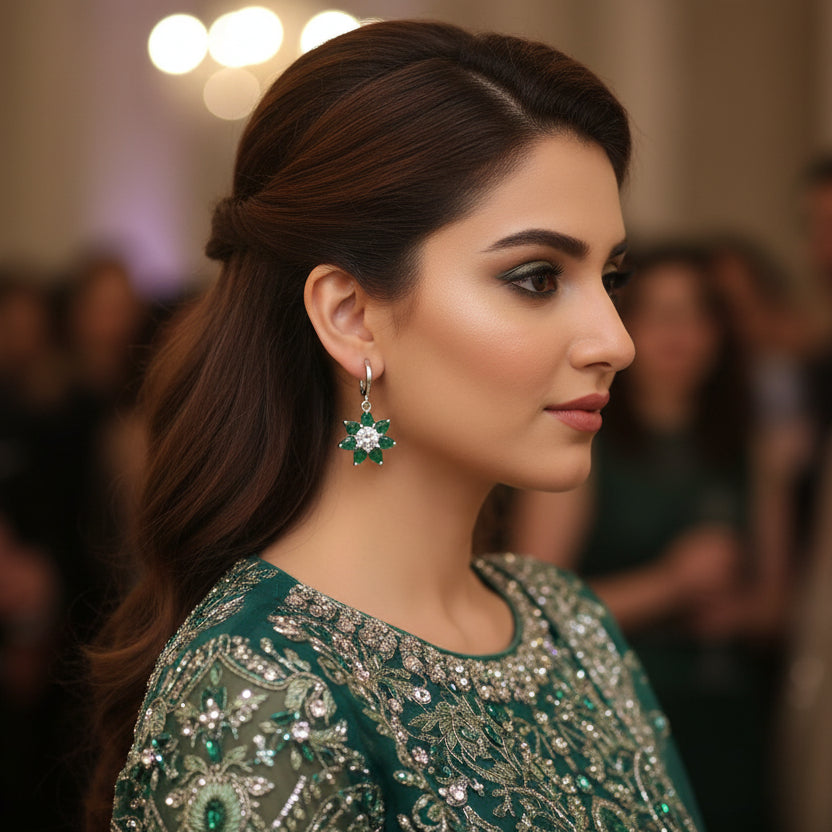 Pair of earrings with green gemstones on a gray background