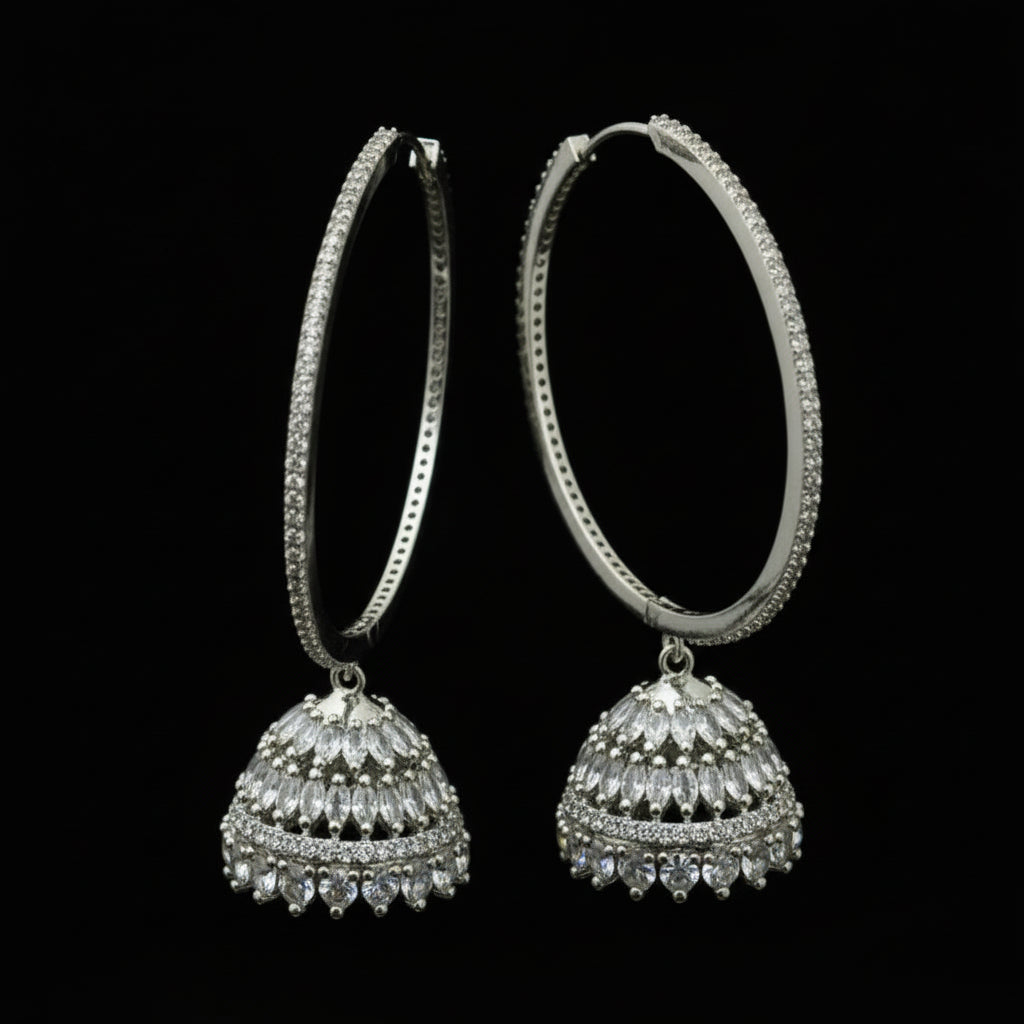 Silver hoop earrings on a black stand with 'Saheli' branding.