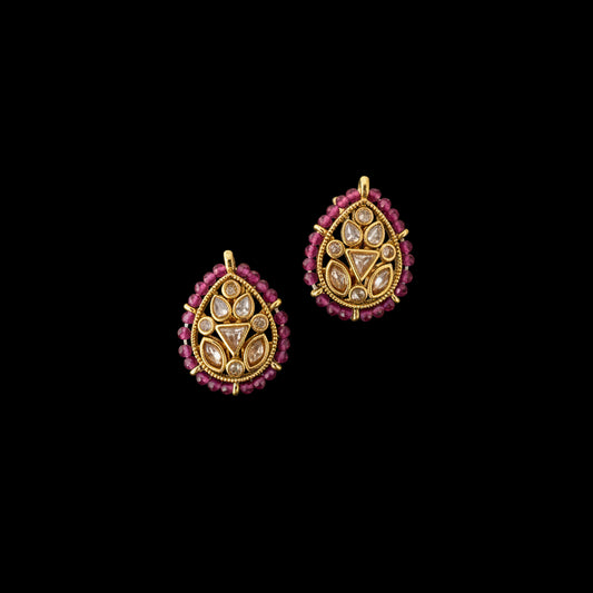 Gold and pink earrings on a gray background with 'SAHELI' branding.