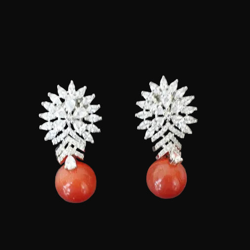 Pair of earrings with snowflake designs and red spherical elements on a gray background