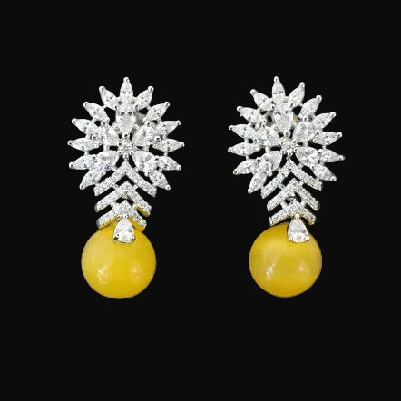 Pair of earrings with silver floral tops and yellow spherical bottoms on a dark gray background