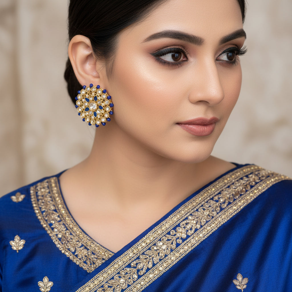 Pair of gold and blue earrings on a dark background with 'SAHELI' branding.