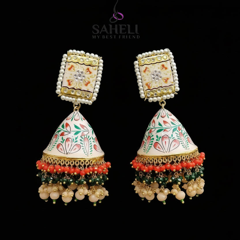 Decorative earrings with intricate designs on a gray background, featuring the brand 'SAHELI'.