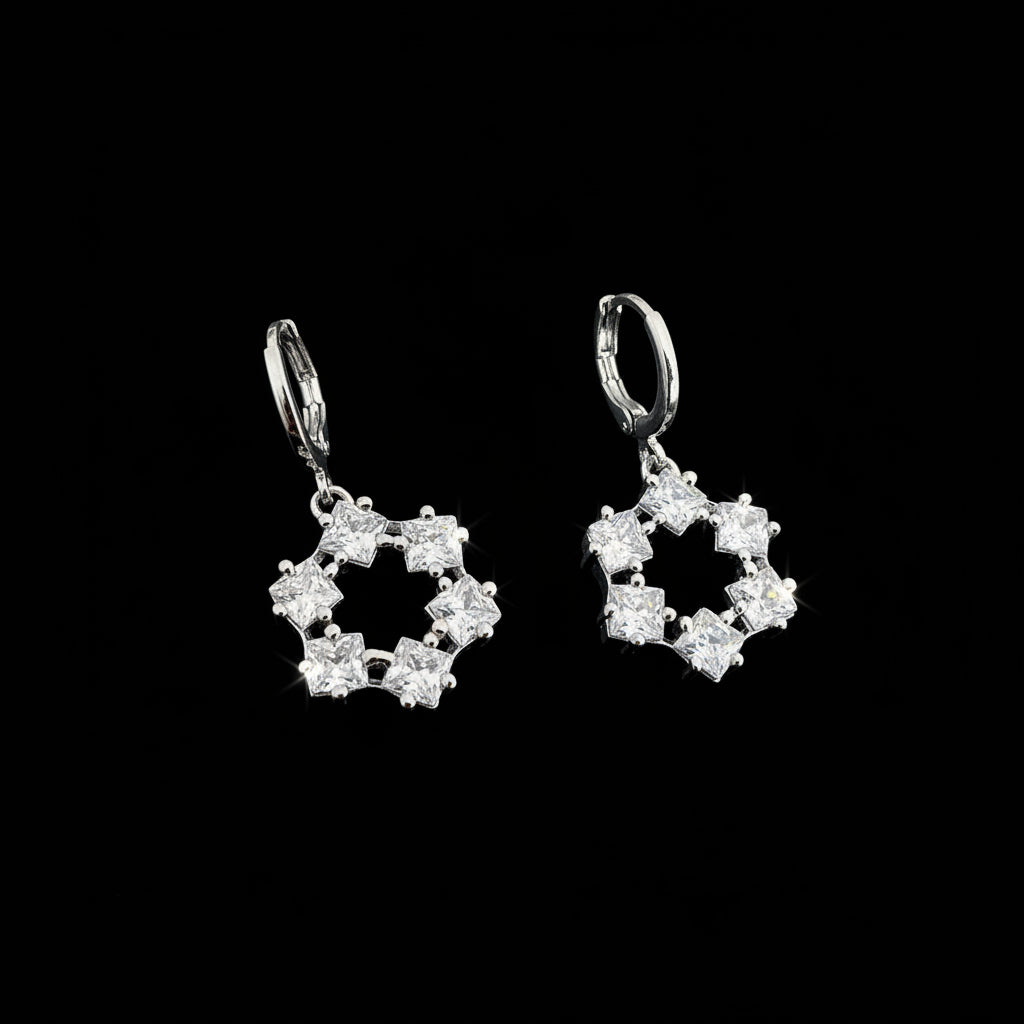 Silver earrings with star-shaped designs on a dark background, branded 'SAHELI'.