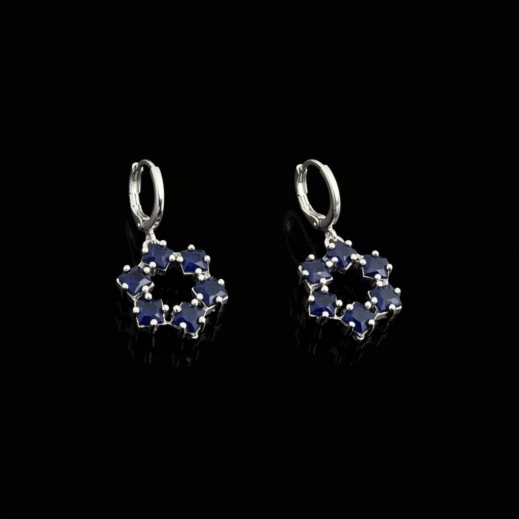 Pair of silver earrings with blue gemstones on a gray background, featuring the brand 'Saheli'.