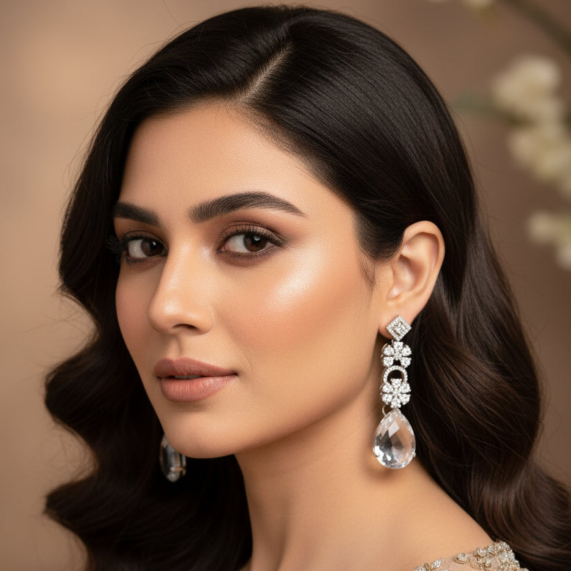 Pair of teardrop-shaped earrings with decorative elements on a dark background