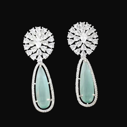 Pair of earrings with floral top and teardrop-shaped gemstone on a gray cushion