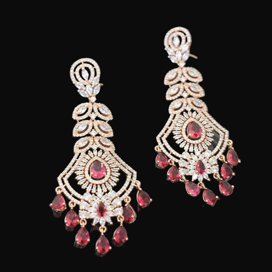 Pair of ornate earrings with red gemstones on a dark background