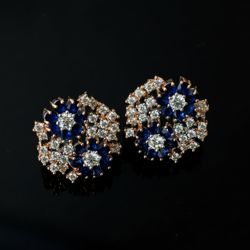 Pair of earrings with blue and silver design on a dark background, featuring the brand 'Saheli'.