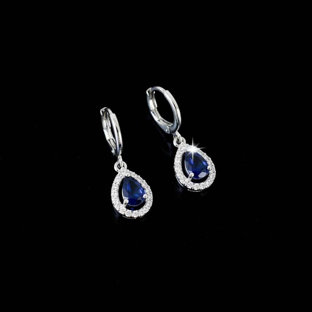 Pair of silver earrings with blue gemstones on a black background
