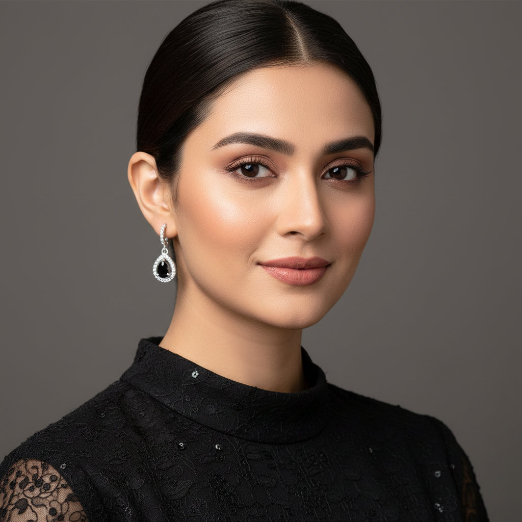 Silver earrings with black stones on a gray background, featuring the brand 'Saheili'.