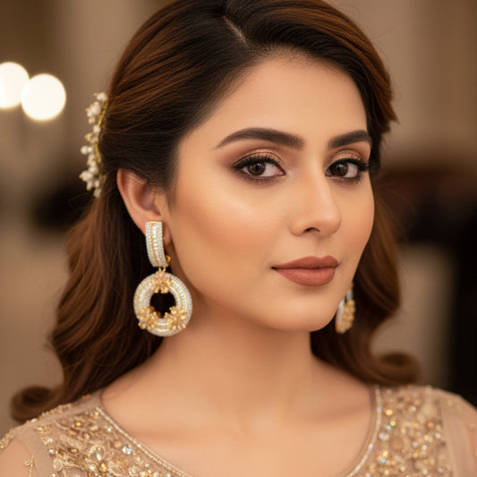 Gold and diamond earrings on a dark background with 'SAHELI' branding.