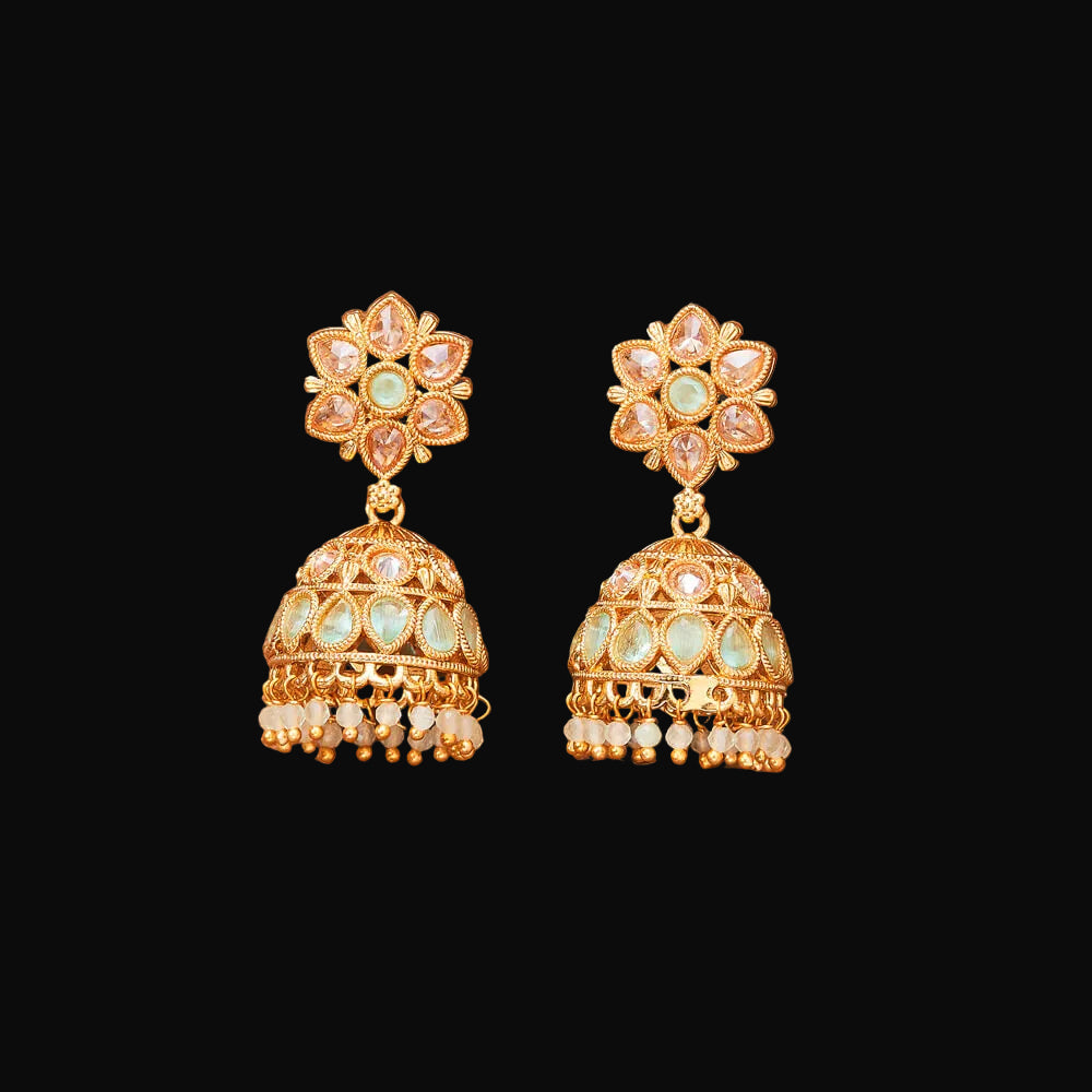 Gold earrings with floral design on a brown background