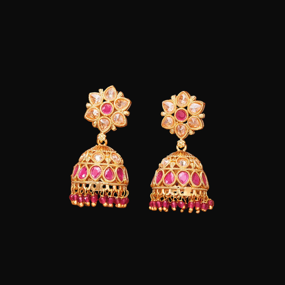 Pair of gold and pink earrings on a brown background