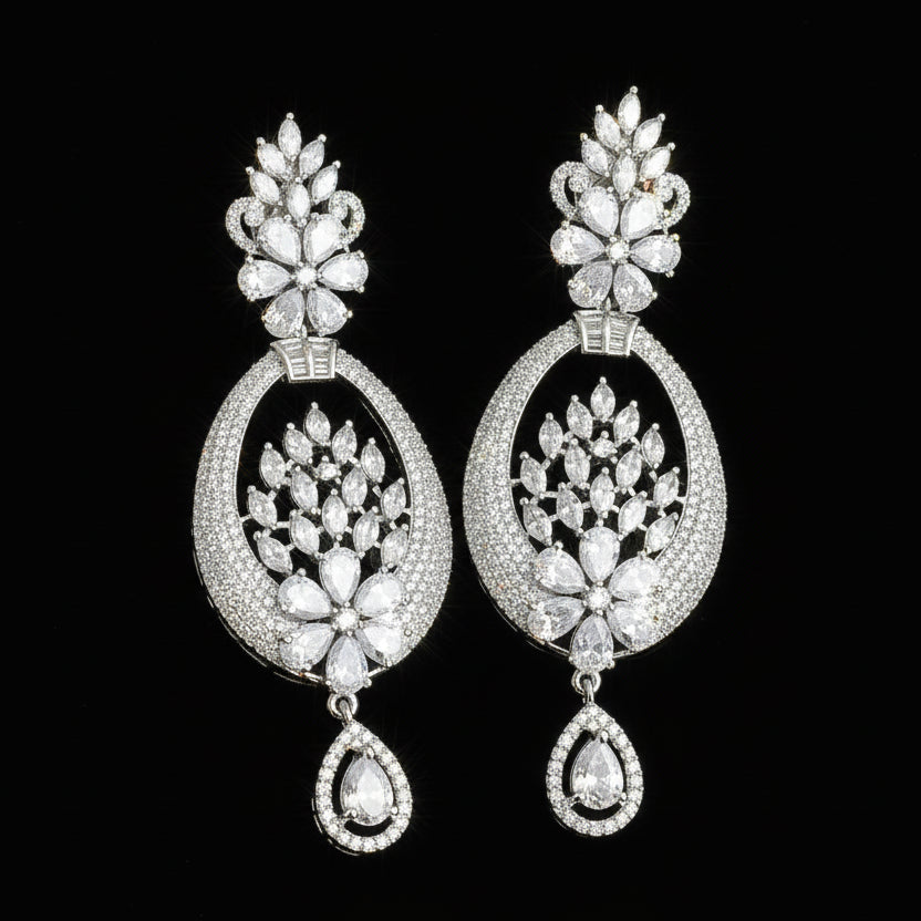 Ornate silver earrings with black accents on a dark background, featuring the brand 'Saheli'.