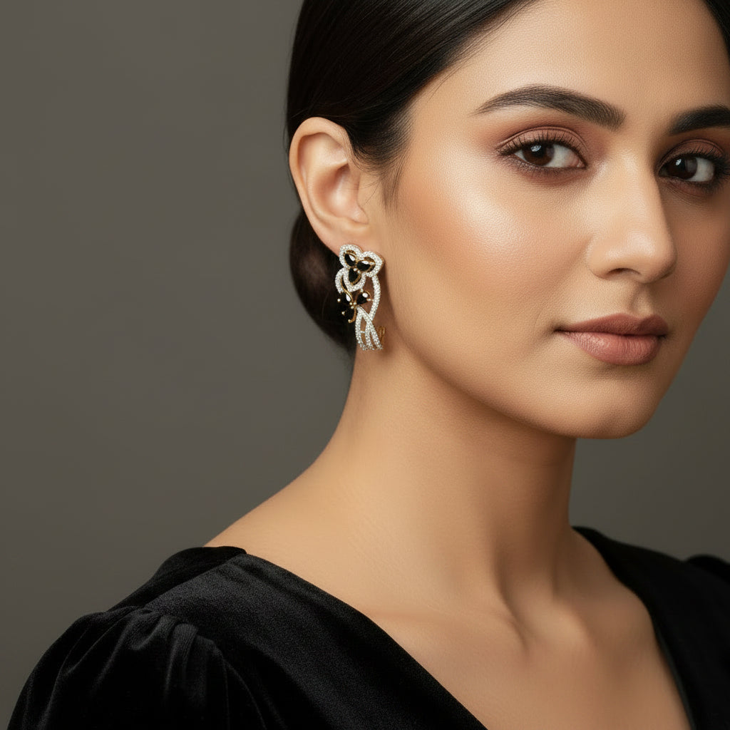 Pair of diamond earrings on a dark gray stand with 'Saheli' branding.