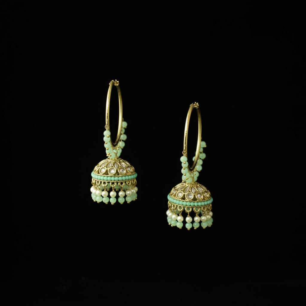 Pair of gold hoop earrings with green beads on a black background