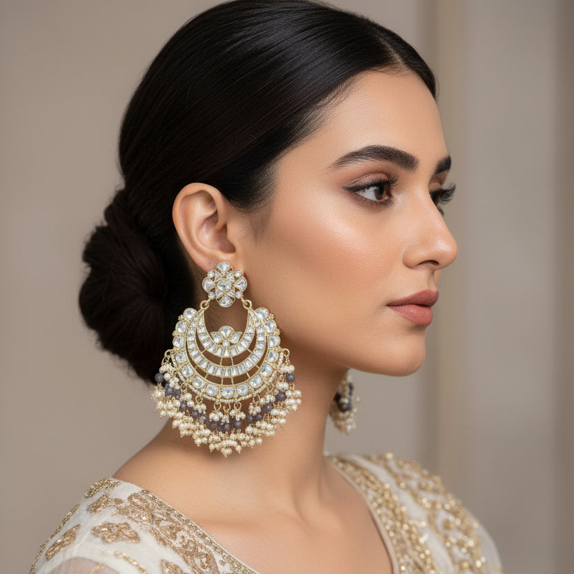Pair of ornate earrings with gold and pearl details on a dark background