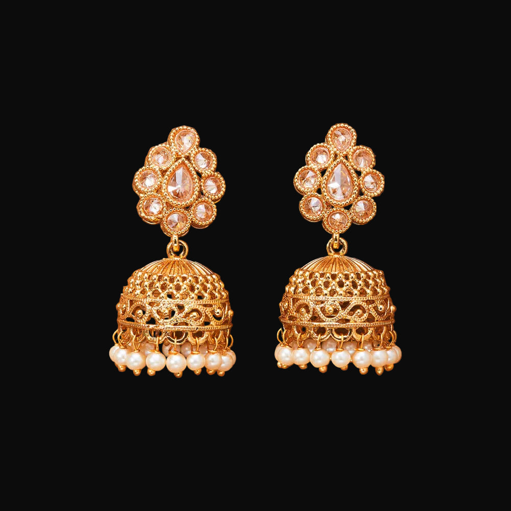 Gold and pearl earrings on a brown background