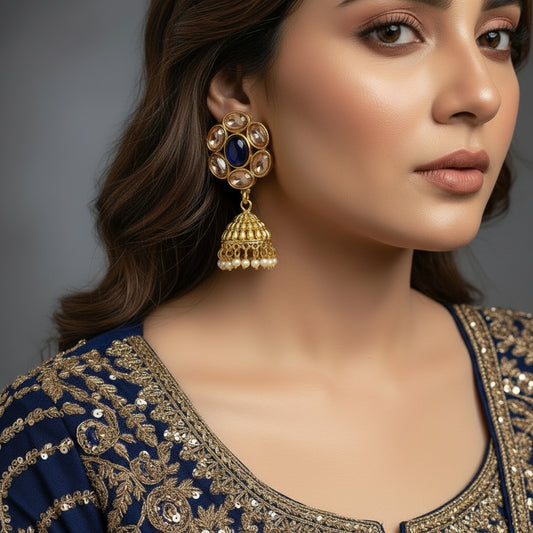 Gold and black earrings on a gray stand with 'Saheli' branding.