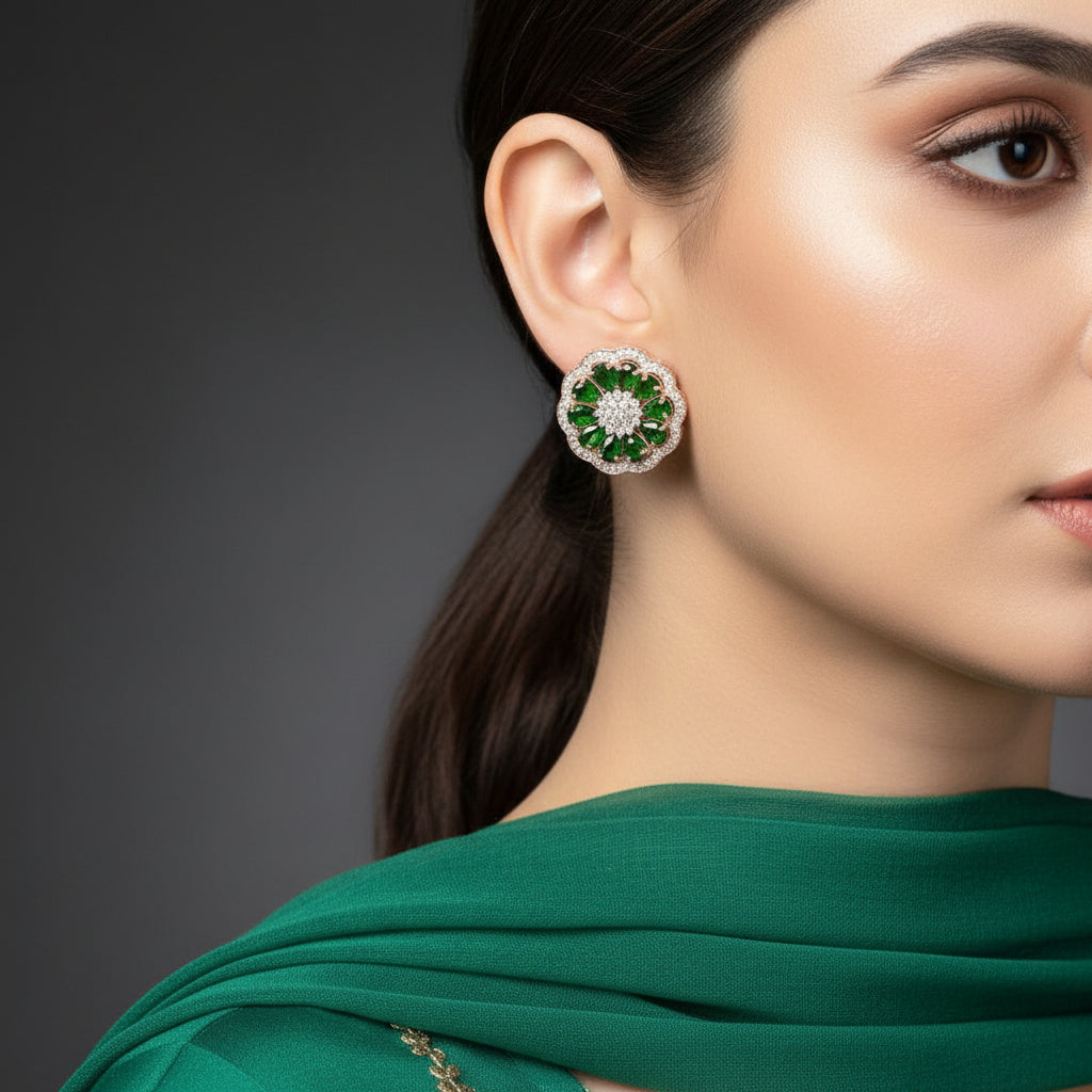 Pair of green gemstone earrings with gold accents on a gray background, featuring the brand 'Saheli'.
