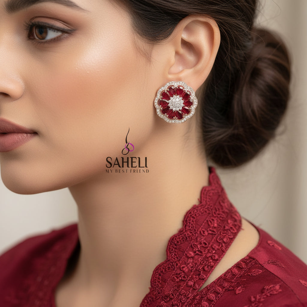 Pair of red and gold floral earrings with 'Saheli' branding on a gray background